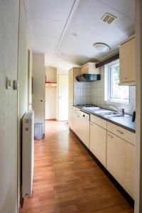 瓦赫宁根Chalet vakantie Wageningen的厨房铺有木地板,配有白色橱柜。