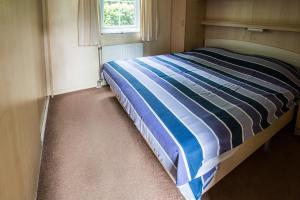 瓦赫宁根Chalet vakantie Wageningen的一间卧室配有一张带蓝色和白色条纹棉被的床
