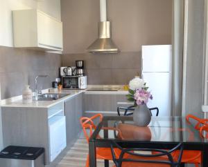 巴塞罗那桑茨之感公寓的厨房配有玻璃桌和橙色椅子