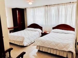 杜伊塔马Hotel Azuay的一间卧室设有两张床,窗户配有窗帘