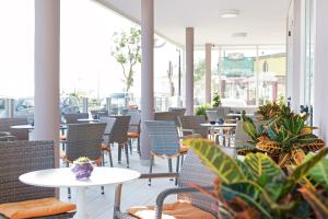 里米尼假日海滩酒店的一间设有桌椅和植物的餐厅