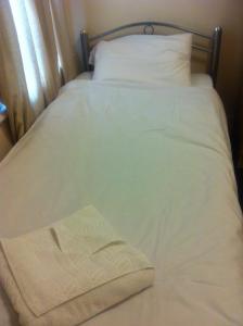伦敦伦敦奥林巴斯酒店的一张带白色床单的床和一本书