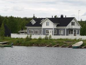 佩洛米耶科亚维度假村的白色的房子,有白色的围栏和水面上的船