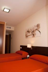 马德里格兰纳德旅馆的一间卧室配有两张带橙色床单和灯的床