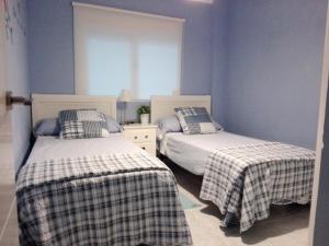 瓦伦西亚甜美卡罗琳公寓的卧室设有两张床铺和蓝色的墙壁