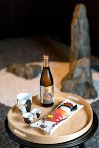 京都R&Run Kyoto Serviced Apartment & Suites的木托盘上一瓶葡萄酒和寿司