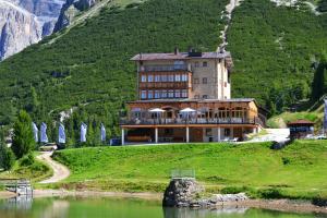 卡纳泽伊Hotel Pordoi Passo Pordoi Vegetarian Hotel的一座位于湖畔小山上的大建筑