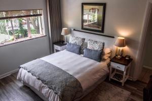开普敦野生橄榄宾馆的一间卧室配有带2个床头柜和2个窗户的床