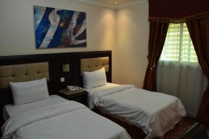 利雅德Manazilna Apartments Riyadh的酒店客房设有两张床和窗户。