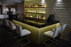 帕拉利亚卡泰里尼斯泽费罗斯酒店的酒吧配有白色椅子和酒精饮料瓶