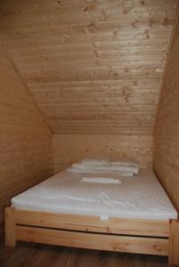 博格泽利卡AURUM Domki Letniskowe的木制客房的一张床位,设有木制天花板