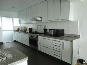 利马San Borja, bello apartamento的厨房配有白色橱柜和炉灶烤箱。