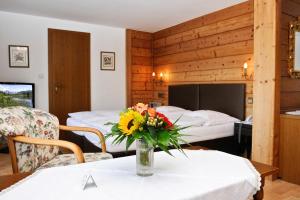 蒂罗尔-泽费尔德海尔格酒店的一间设有两张床的房间,一张桌子上放着花瓶