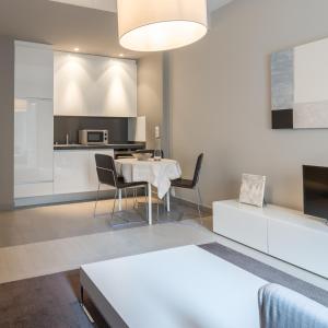 卢森堡四星级公寓式酒店的厨房以及带桌椅的起居室。