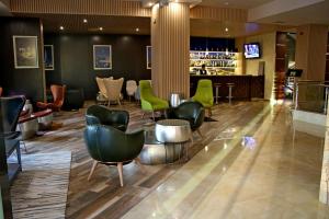 瓦尔纳Hotel Golden Tulip Varna的大堂设有绿色椅子和酒吧