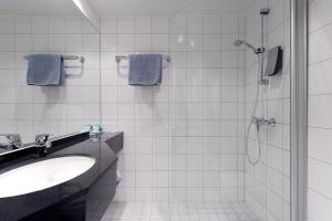 特罗姆瑟奥罗拉克拉丽奥连锁酒店的白色瓷砖浴室设有水槽和淋浴