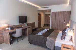 多瑙斯特雷达Hotel Thermalpark的酒店客房配有一张床、一张书桌和一台电视。