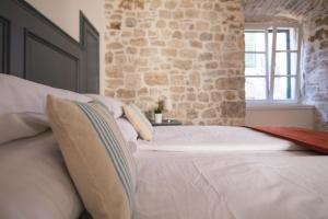 希贝尼克地中海豪华客房旅馆的卧室配有白色的床铺和石墙