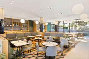 悉尼悉尼机场曼特拉酒店的餐厅设有桌椅和窗户。