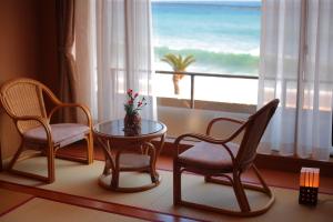东伊豆町希纳日式旅馆的一间设有两把椅子、一张桌子和一个窗户的房间