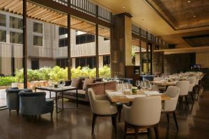 新德里新德里玫瑰色之屋酒店的餐厅设有桌椅和窗户。