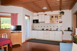 奥蒂塞伊Apartments Dolina的厨房配有白色橱柜和平面电视。
