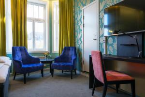 特隆赫姆Thon Hotel Nidaros的酒店客房带蓝色椅子、桌子和床