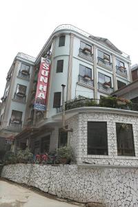 萨帕Son Ha Hotel SAPA的一座高大的白色建筑,有石墙