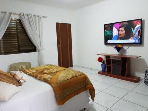 亚美利加纳希达吉布鲁玛酒店的一间卧室配有一张床和一台平面电视