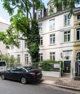 美因河畔法兰克福DIRAZI Guesthouse & Apartments GmbH的停在白色建筑前的黑色汽车
