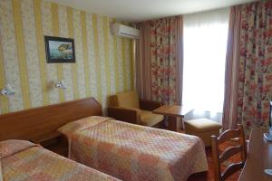 阳光海滩Olymp Hotel的酒店客房,配有两张床、一张桌子和一把椅子