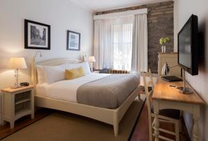 魁北克市Auberge Saint-Pierre的一间卧室配有一张床、一张书桌和一台电视