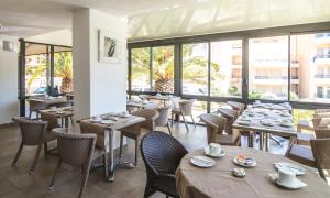 卡尔维马里亚纳酒店的餐厅设有木桌、椅子和窗户。