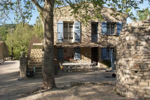 赛尼翁Villa Les Carlets的石头房子,带桌子和一棵树