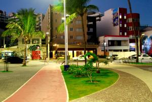萨尔瓦多Rede Andrade Mar Hotel - Rio Vermelho的夜间在城市里走一条种有棕榈树的走道