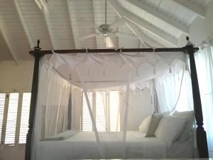 Five Islands VillageAloe Villa的卧室配有带白色窗帘的天蓬床