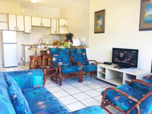 马盖特Dumela Margate Flat No 4的一间带蓝色椅子的客厅和一间厨房