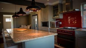 克尼斯纳Knysna Forest View的厨房配有花岗岩台面和红色橱柜