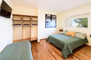 玛德琳港托斯卡旅舍的一间卧室配有一张床和一台平面电视