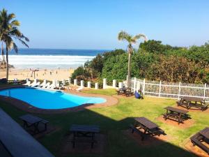 马盖特Dumela Margate Flat No 9的后院设有游泳池和野餐桌,海滩