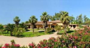 奥尔梅多伊维尼缇农庄酒店的一座带棕榈树和鲜花的花园的房子