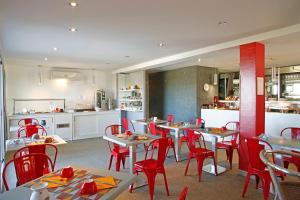 利勒鲁斯海滨喷泉酒店的一间带桌子和红色椅子的餐厅和一间厨房