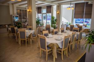 都拉斯Hotel Vila Koral的餐厅设有白色的桌椅和窗户。