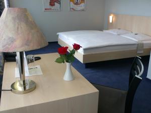 萨尔布吕肯梅兰海伦巴德萨那温泉酒店的酒店客房配有一张床和一张带台灯的桌子