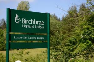 奥尼赫Birchbrae Highland Lodges的伯明翰高原山林小屋的绿色标志