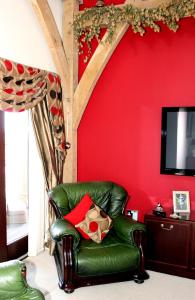 拉纳克Backbrae House Luxury B&B的红色墙壁的房间里一张绿色的皮椅