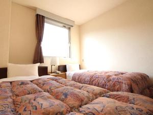 Okaya奥库尼酒店（皇家旅馆集团）的酒店客房设有三张床和窗户。