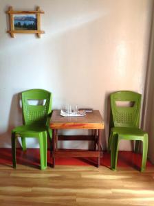 西隆Holly Lodge Guest House的两张绿色椅子坐在木桌旁