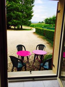Lentla ferme de Martine的窗户外的粉红色桌子和椅子
