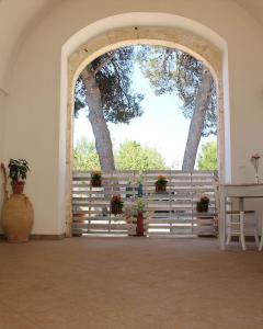 赛拉诺B&B Masseria Donna Carlotta的拱门,有栅栏,桌子和树